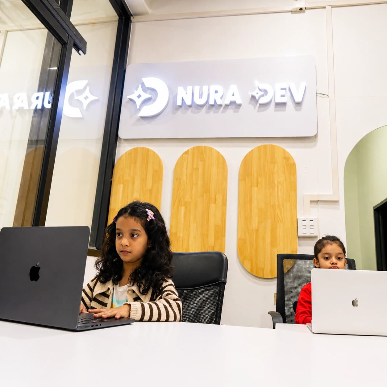 Young learners using laptops inside the Nura Dev computer campus