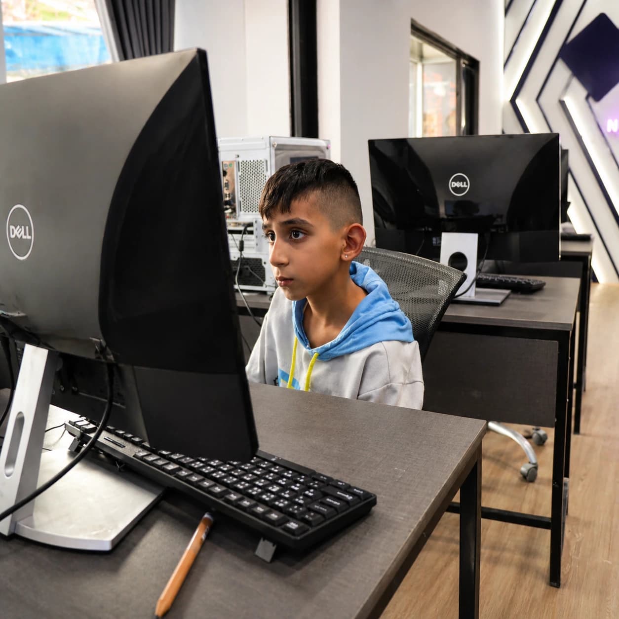 Young learner focused on desktop computer practice at Nura Dev