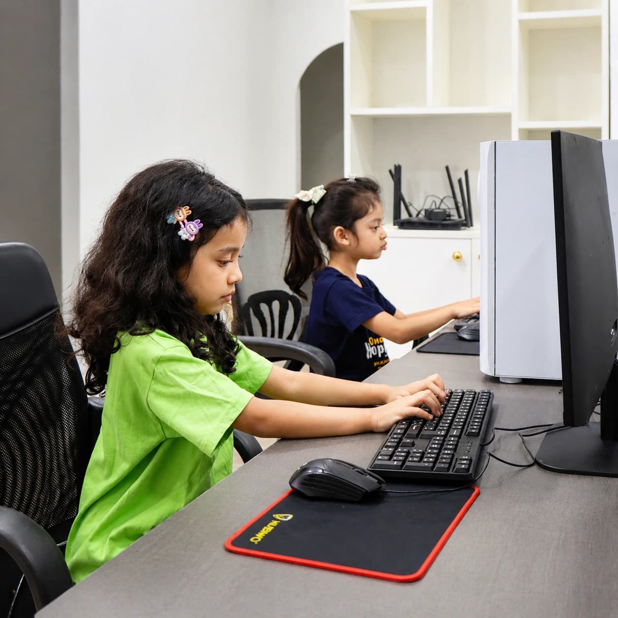 Two young learners practicing keyboard skills together at Nura Dev
